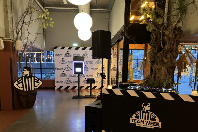 Branded photobooth and custom Foot Locker backdrop setup at a corporate team event venue in the Netherlands, with DJ booth in the foreground - Smilen.nl