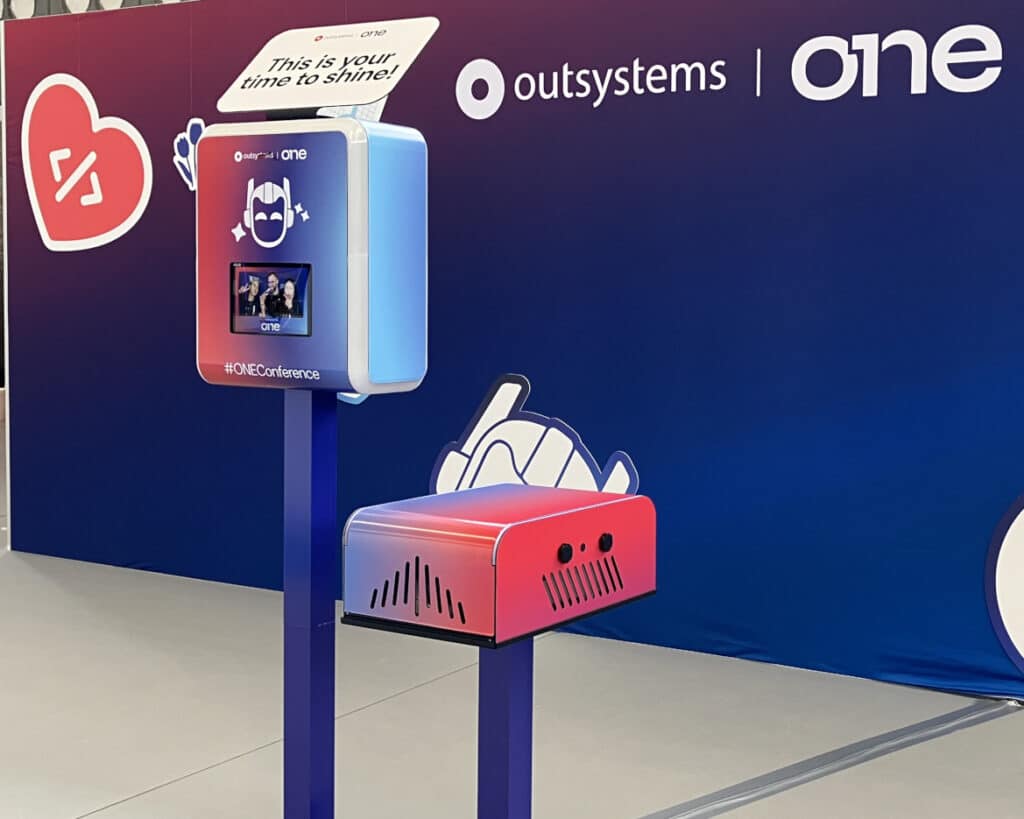Branded photo booth and printer stand at OutSystems ONE 2026 Amsterdam corporate event