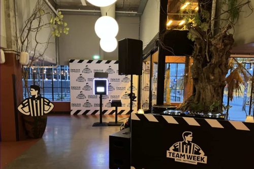 Branded photobooth and custom Foot Locker backdrop setup at a corporate team event venue in the Netherlands, with DJ booth in the foreground - Smilen.nl