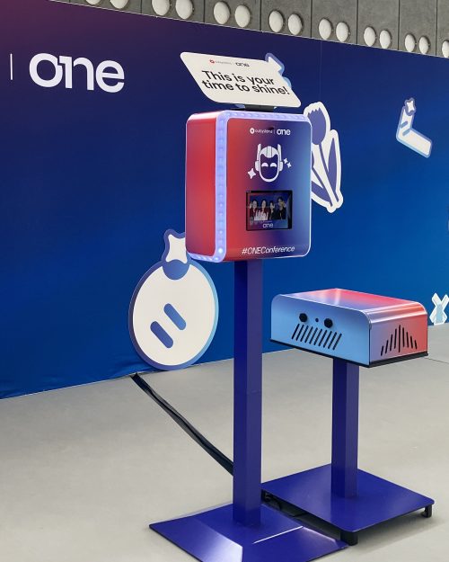 Branded photo booth and matching printer stand setup at OutSystems ONE 2026 corporate event